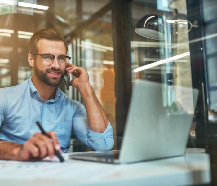 Man in front of a computer talking on the phone