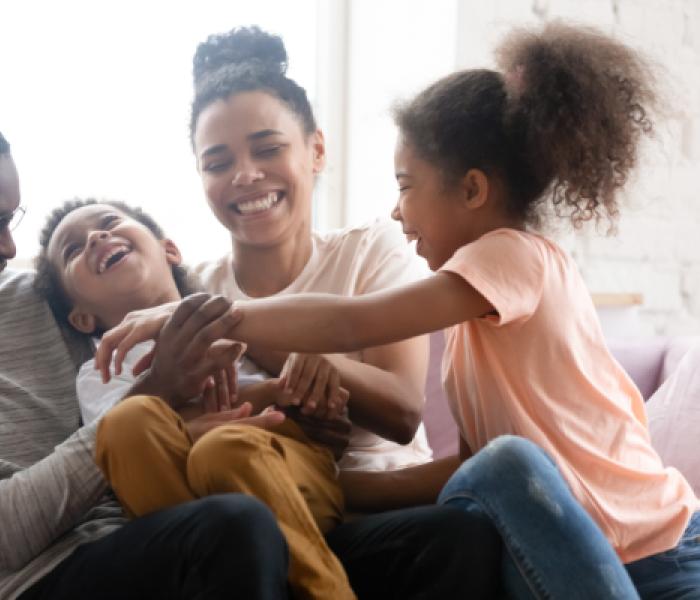 Family of four sitting on couch and laughing image