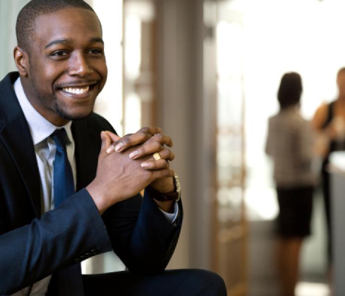 Man wearing a suit and tie, sitting and smiling image