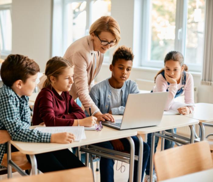 Teacher showing students something on a laptop computer image