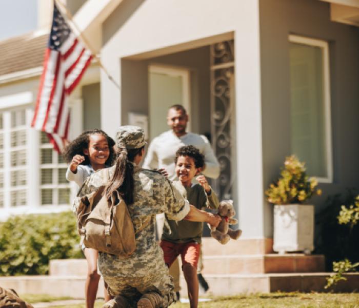 family hugging a soldier returning home