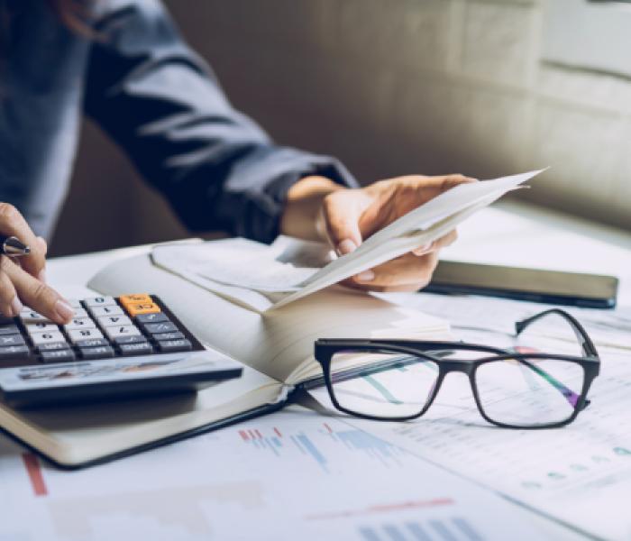 Person at a desk using a calculator and handling paperwork image