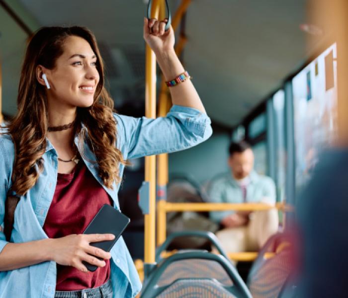 Woman riding a bus, standing up and holding an overhead railing image