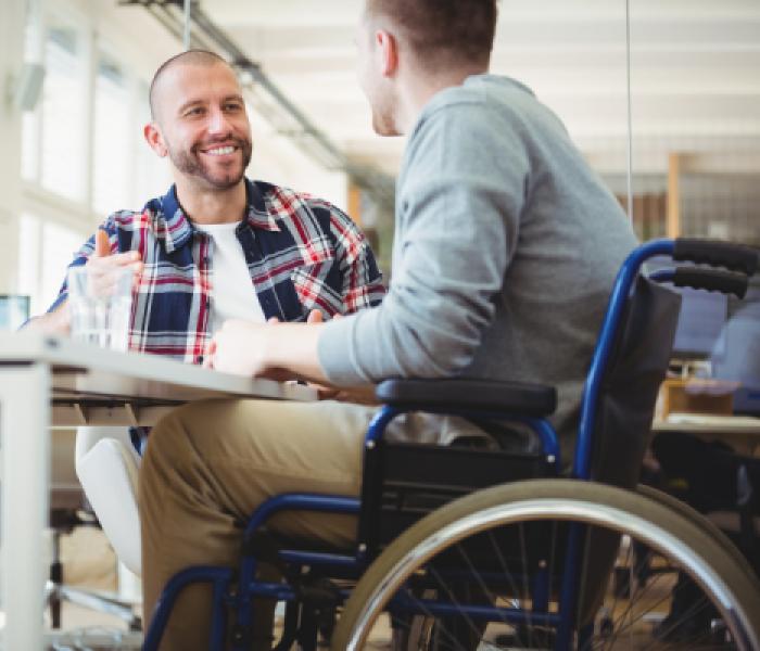 Two men sitting at a table, one uses a wheelchair image