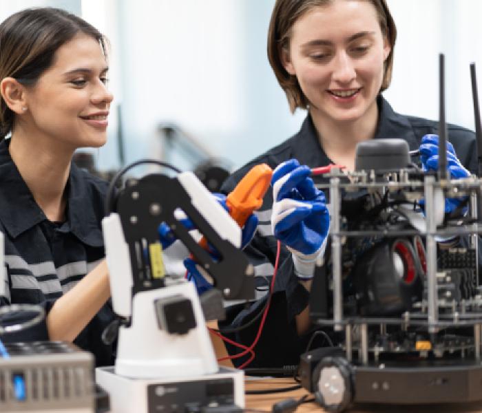 Two people working with robotics equipment image